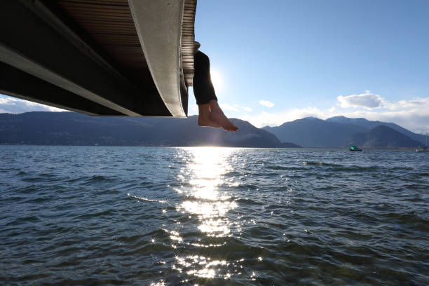 istock Woman dangles feet over dock's edge 1142179720