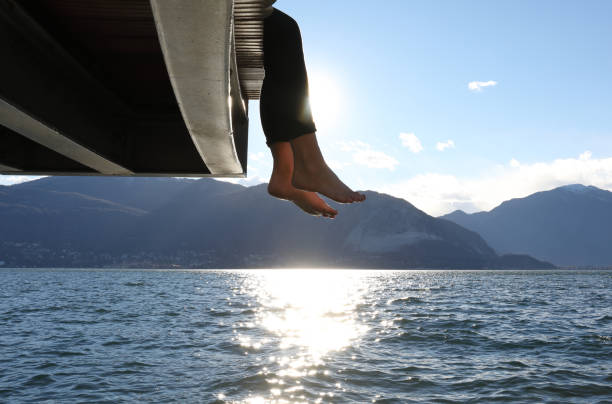 istock Woman dangles feet over dock's edge 1142179731
