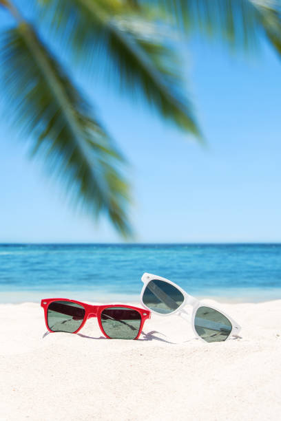 istock Sunglasses lying on tropical sand beach -- Tropical vacation concept 1142183890