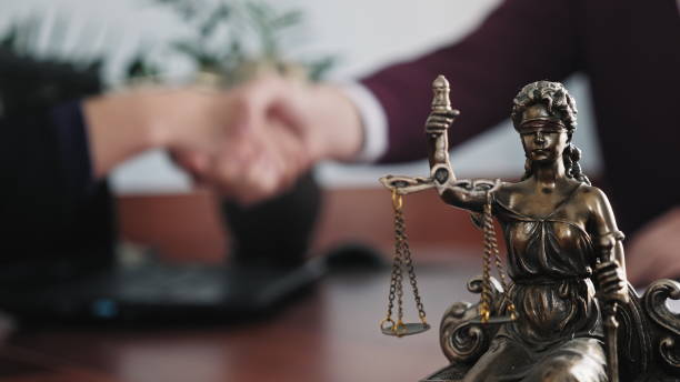 Statuette of lady justice on the table close-up Statuette of lady justice on the table close-up against the background of the handshake of a woman and a man criminal stock pictures, royalty-free photos & images