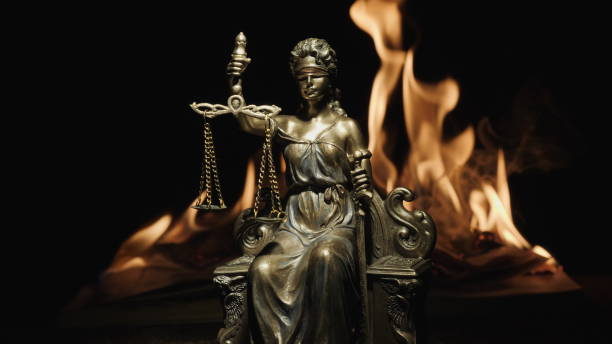 Statue of Lady Justice on the background of the flame of a burning book Statue of Lady Justice on the background of the flame of a burning book. Slow motion video book burning stock pictures, royalty-free photos & images