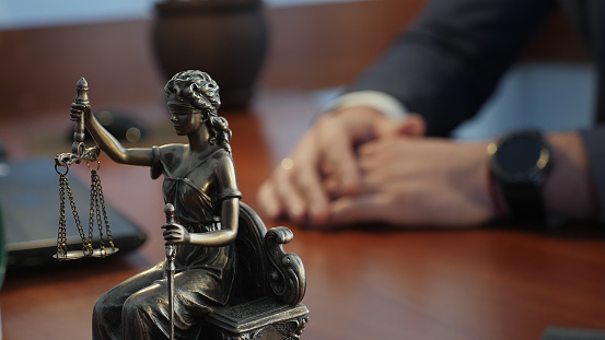 Statue of justice on the table against the background of the hand gestures of a man, a lawyer or a judge