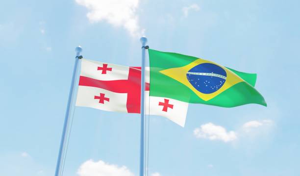 istock Brazil and Georgia, two flags waving against blue sky 1142185544