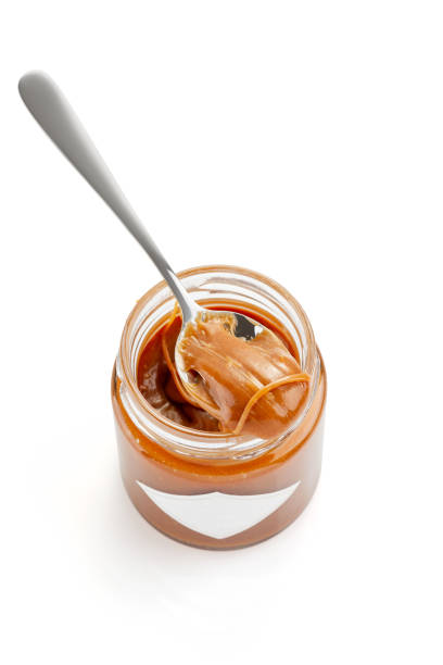 ложка с соленым карамельным соусом на банке, выделенной на белом - syrup jar sticky isolated objects стоковые фото и изображения