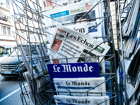 Paris, France - 29 Mar 2019: Newspaper stand kiosk selling press with senior male hand buying latest featuring  on front cover