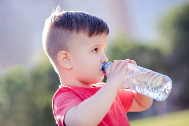 istock handsome boy drinks clear water from a bottle on a sunny day outside 1142190238