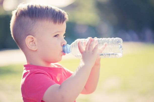 istock handsome boy drinks clear water from a bottle on a sunny day outside 1142190320