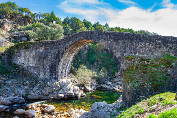 ponte romana de pedra, parte de uma estrada romana, sobre o desfiladeiro rochoso do rio de alardos. cercado pela natureza em sierra de gredos. madrigal de la vera, cáceres, extremadura, espanha - travel avila castilla y leon spain - fotografias e filmes do acervo