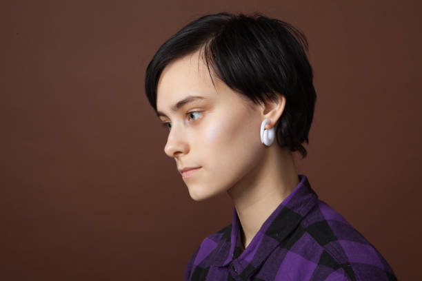 studio portrait of an attractive 18 year old woman with short hair on a brown background. - earring human face brown hair black hair imagens e fotografias de stock
