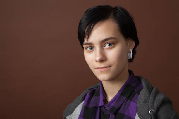 studio portrait of an attractive 18 year old woman with short hair on a brown background. - earring human face brown hair black hair imagens e fotografias de stock