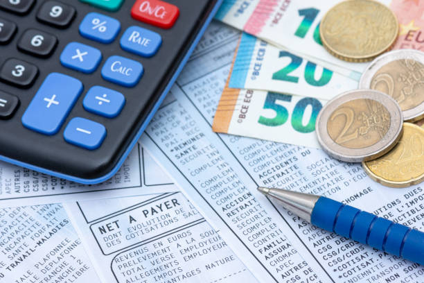 French payroll with income tax deduction. French payroll with social contributions and income tax deduction, mandatory in France since January 2019, along with a calculator, a pen, and euro coins and bank notes capital budget pictures stock pictures, royalty-free photos & images