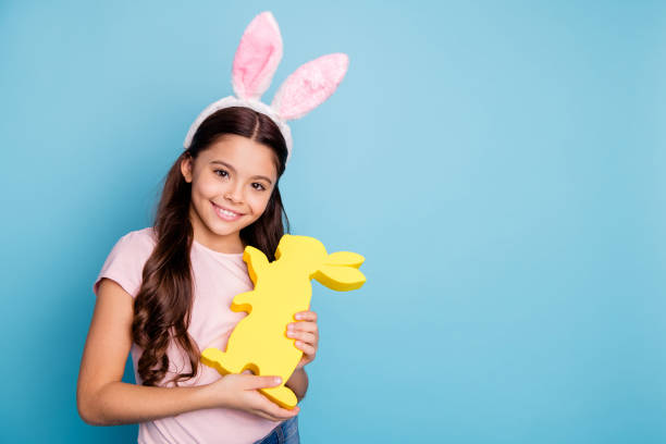 closeup photo portrait of lovely cheerful pretty with beaming toothy smile charming in casual t-shirt girl holding hugging golden colored rabbit in hands isolated pastel background - offspring child toothy smile beautiful imagens e fotografias de stock