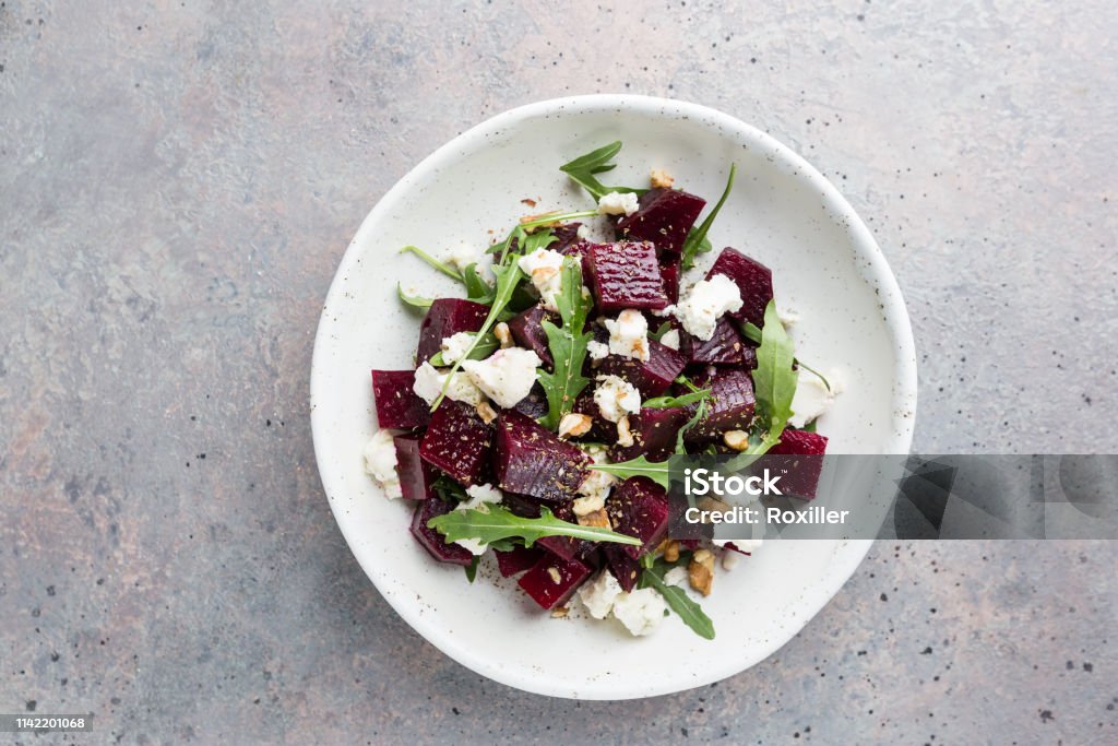 beetroot salad with blue cheese beetroot salad with blue cheese, arugula and walnut in a white plate on gray background, top view Salad Stock Photo