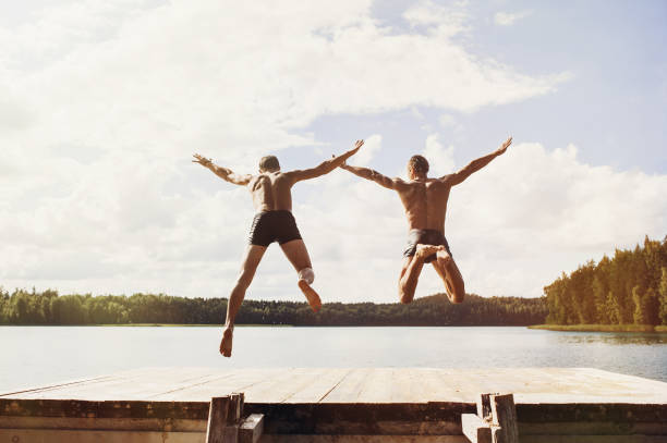 istock Summer fun. Friends jumping from jetty into the lake 1142202293