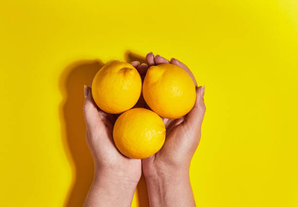 istock Lemon in hand on yellow background. Flat lay, top view, copy space . Food concept. 1142205995