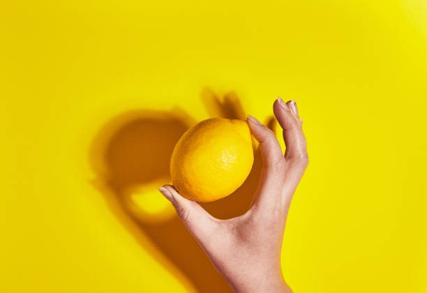 istock Lemon in hand on yellow background. Flat lay, top view, copy space . Food concept. 1142206263
