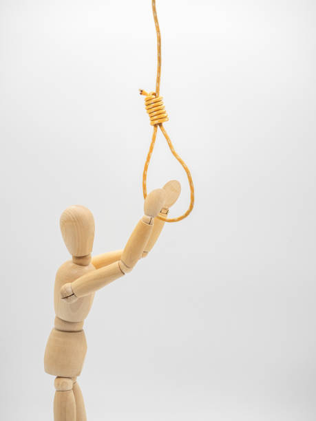 istock Miniature wooden doll is pulling hands to hanging rope and touch gallow noose isolated on white. Close up view. 1142207326