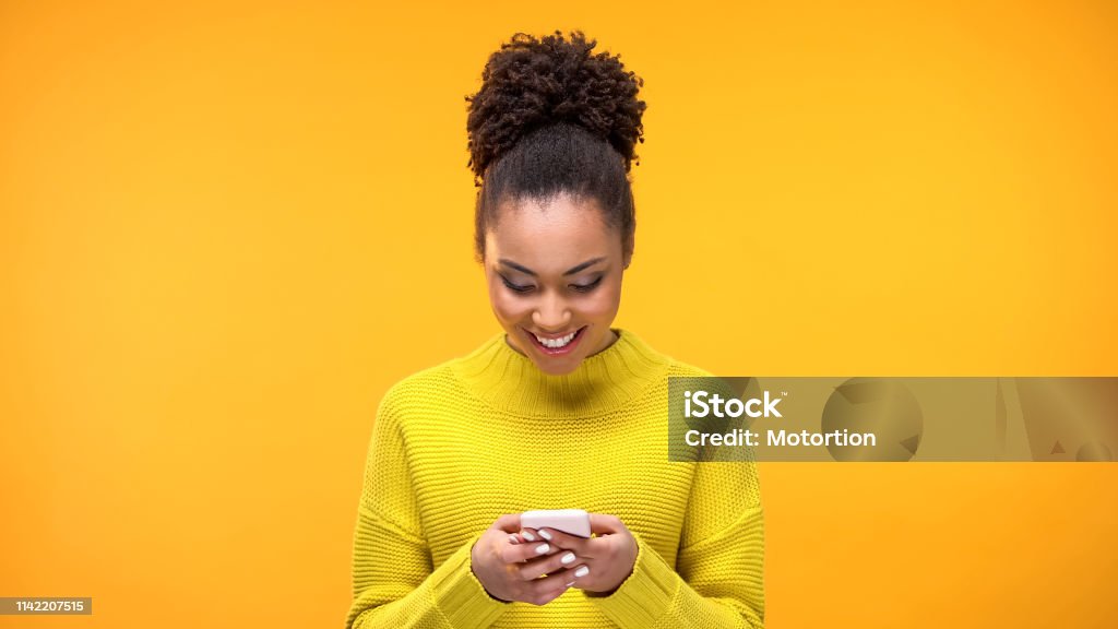 Smiling African-American woman chatting on smartphone, modern technology, app Mobile Phone Stock Photo