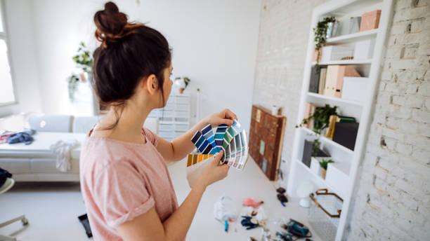Choosing the right color for my wall Young woman during reconstruction of apartment, holding color chart and choosing the right color for the wall household equipment photos stock pictures, royalty-free photos & images