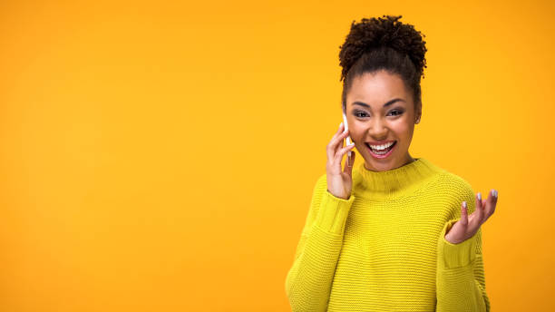 istock Joyful african female talking phone on yellow background, mobile communication 1142207628