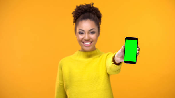 istock Happy female student showing smartphone with green screen, social network app 1142207801