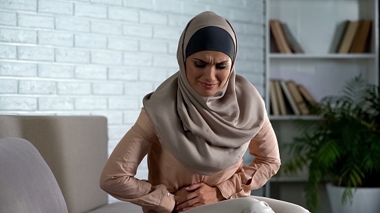 Mujer musulmana joven sintiendo dolor de estómago, sufriendo de gastritis problema photo
