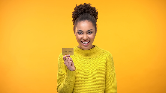Black woman holding golden credit card, VIP banking programs for rich people
