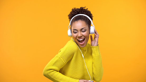 Cheerful afro-american woman in headset enjoying favorite song by radio app