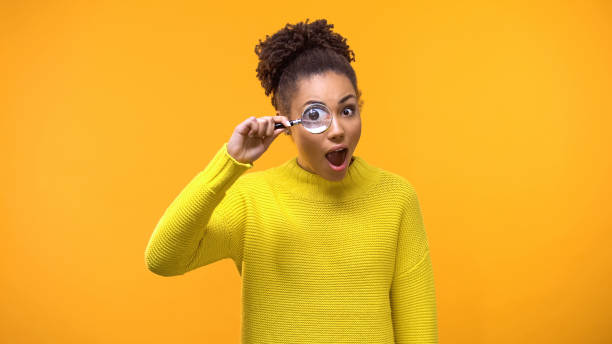 istock Curious afro-american woman looking magnifying glass, having fun, surprise 1142209314