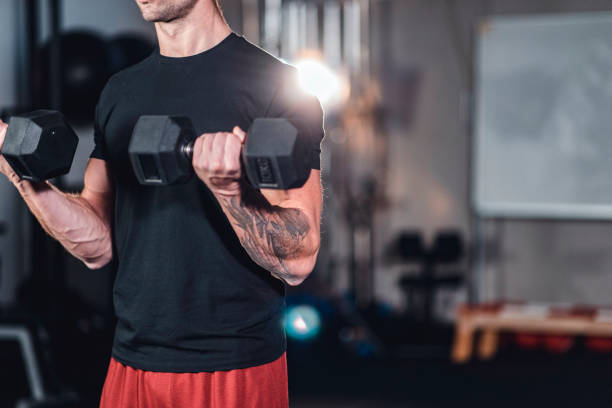 istock Caucasian muscular man doing bicep curls using dumbbells in the gym 1142215474
