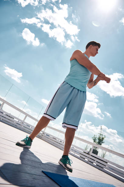 istock Athlete is stretching arm on sunny terrace 1142216966