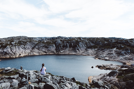 Woman enjoying the view of lake and mountains during her hiking trip in South Norway