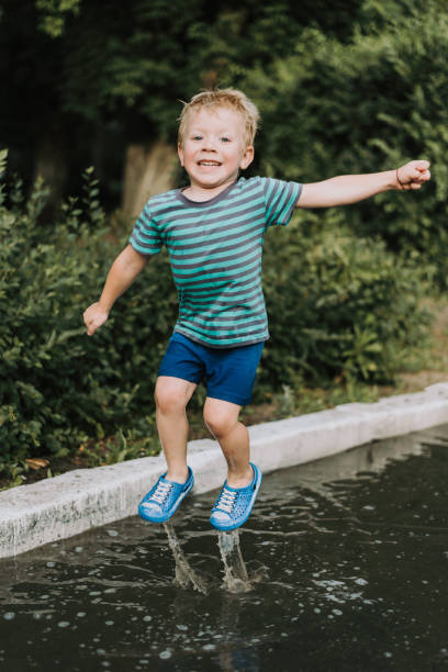 istock little boy jumping in a puddle in summer 1142228345