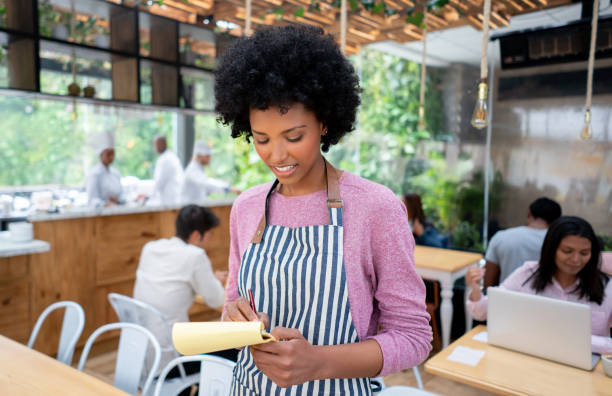 istock Waitress working at a cafe writing on a notepad and smiling 1142230247