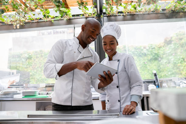 chefs afroamericanos en un restaurante mirando el menú en una tableta digital - food dining cooking multi colored fotografías e imágenes de stock