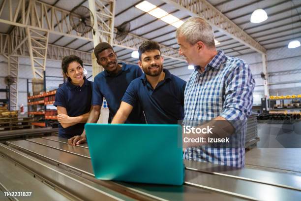 Instructor Explaining Trainees Over Laptop Stock Photo - Download Image Now - Factory, Computer, Trainee