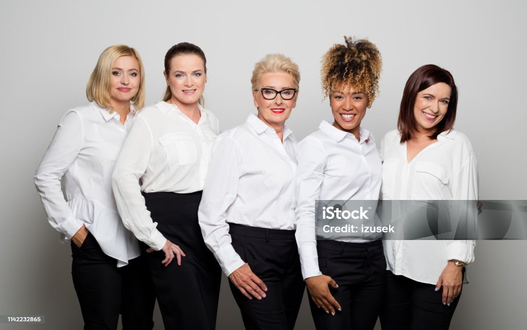 Portrait of smiling female owners in studio Portrait of smiling business owners standing side by side. Confident colleagues are wearing uniform. They are against white background. Business Stock Photo