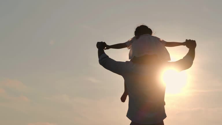 Asian baby girl ride the neck of father.Dad and baby girl playing together outdoors on a summer.Happy family watching the sunset on the beach.Holiday travel concept.Vacations - iStock