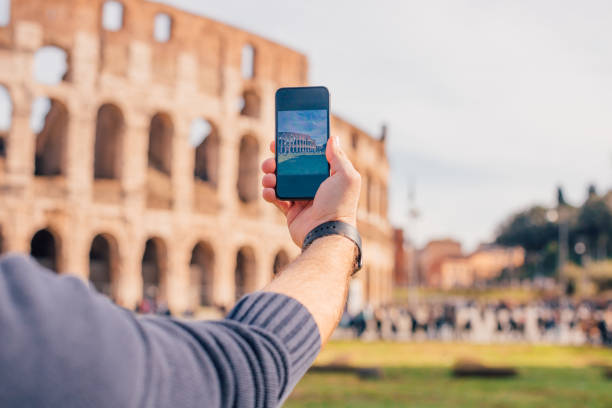 Male hand with smartphone taking picture of colosseum (Rome, Italy) stock photo