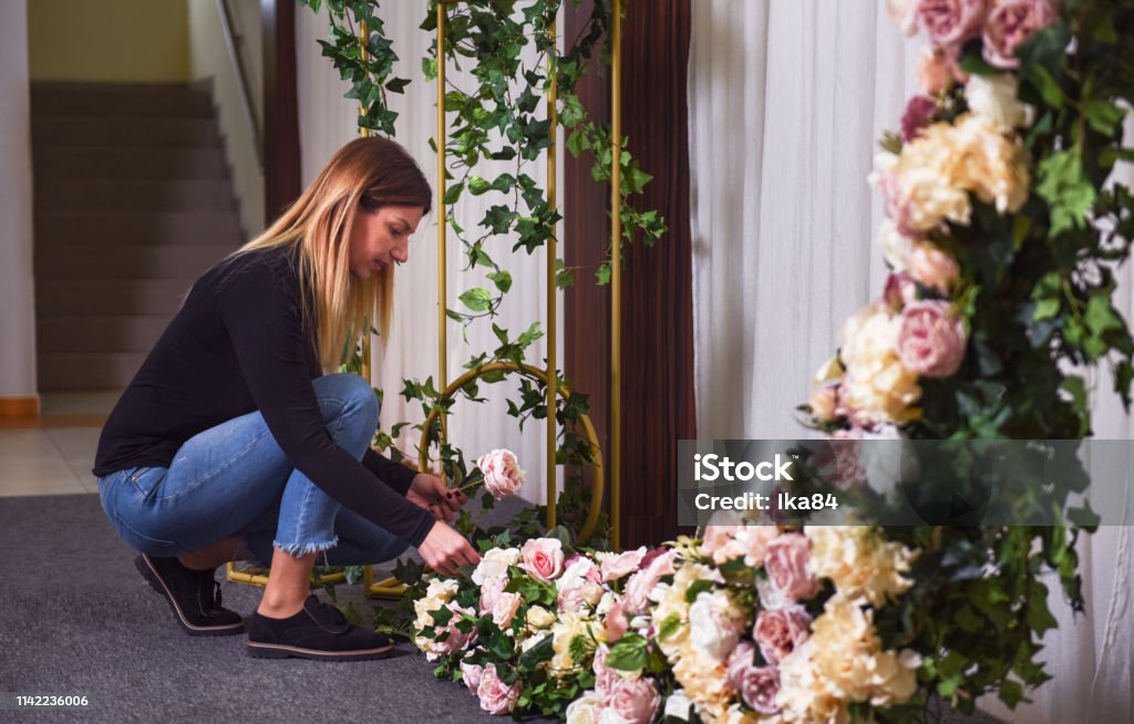 Woman arranging flowers for wedding celebration Woman arranging flowers and decorations for wedding celebration Arranging Stock Photo
