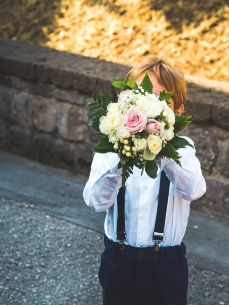Little cute ring bearer at garden wedding playing with flower bouquet