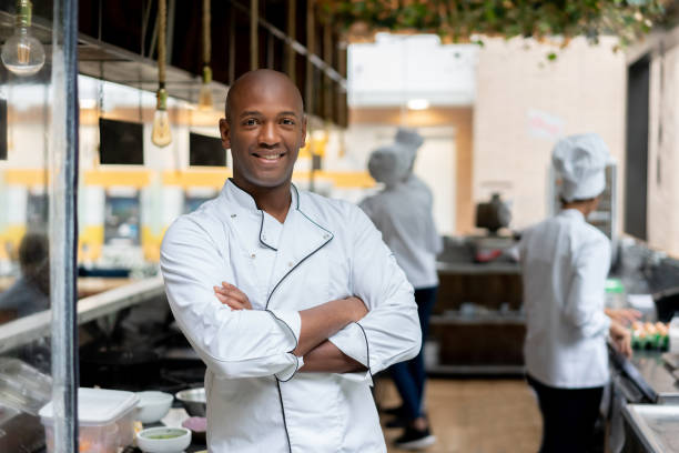 chef heureux travaillant dans une cuisine dans un restaurant - chef restaurant cooking african descent photos et images de collection