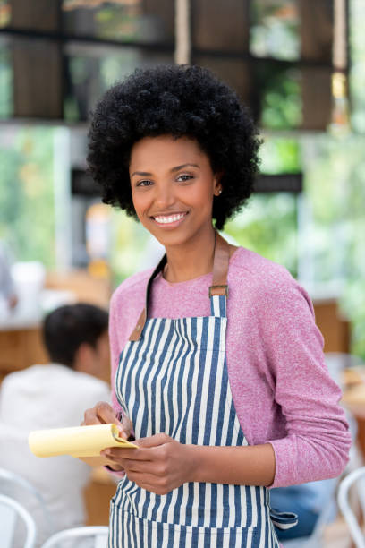istock Beautiful African American waitress working at a restaurant holding a notepad and smiling 1142243837