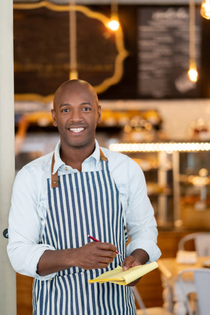 istock Happy waiter working at a restaurant and smiling 1142243911