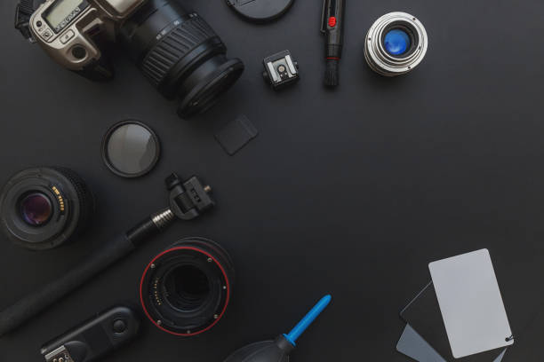 istock Photographer workplace with dslr camera system, camera cleaning kit, lens and camera accessory on dark black table background 1142244109