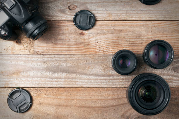 istock Camera lenses and a dslr digital camera on a wooden table, top view 1142244711
