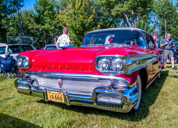 Moncton, New Brunswick, Canada - July 11, 2009: 1958 Oldsmobile 88 two door hard top on display at 2009 Atlantic Nationals Automotive Extravaganza in Centennial Park. People walk among the classic cars and a man relaxes in a lawn chair near a vintage car.