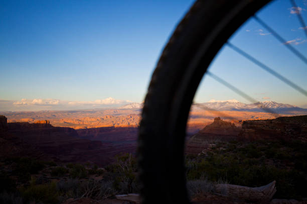 Moab Utah Mountain Biking A view of a mountain bike wheel and the snowcapped La Sal Mountains near Moab, Utah, USA. la sal mountains stock pictures, royalty-free photos & images