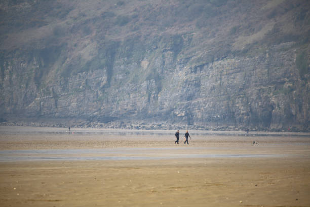 coppia che esercita il loro cane camminando lungo i famosi appartamenti di sabbia a pendine sands.  il 25 settembre 1924 il maggiore sir malcolm campbell ha stabilito un record mondiale di velocità terrestre di 146,16 mph (235,22 km/h) qui nella sua auto  - h major foto e immagini stock