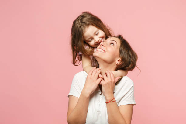 ライトの服の女性はかわいい子供の赤ちゃんと一緒に楽しんでいます。母、小さな子供の娘は、パステルピンクの壁の背景、スタジオの肖像画に分離しました。母の日、愛の家族、親の子供� - isolated little girls two people child ストックフォトと画像